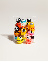 a small plastic package of candy with eyes and other colorful decorations for Halloween, hyper-realistic pop