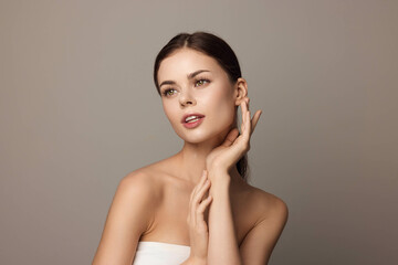 Wall Mural - Beautiful young woman with hands on face, gray background, skin care and beauty concept