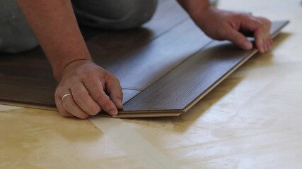 Poster - Close-up of a man kneeling and installing laminate flooring in a home.
