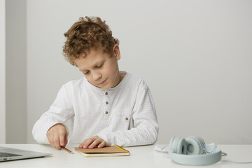 Smiling teenage boy using a laptop at home for elearning and online education The cute Caucasian student is sitting at a desk, typing on a notebook, fully engaged in a virtual lesson His happy