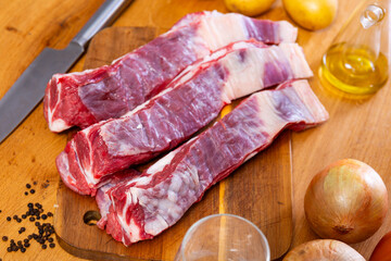 Poster - Fresh raw pork ribs with potatoes, onions and black pepper on wooden table in kitchen