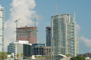 Wide shot Looking north from Demens Landing Park over bright blue water to St. Petersburg, Florida cityscape . Bright  blue and white sky. Green trees and construction crane.
