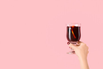 Sticker - Female hand with glass of warm mulled wine on pink background