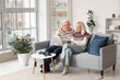 © Pixel-Shot - Mature couple reading magazine on sofa at home