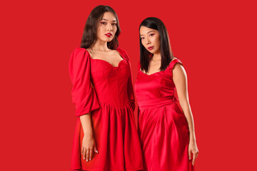 Wall Mural - Beautiful young Asian women in stylish elegant outfits on red background