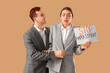 © Pixel-Shot - Business woman holding paper with text STOP HARASSMENT and her male colleague on beige background
