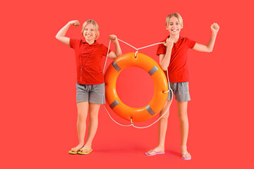 Wall Mural - Happy little children lifeguards with ring buoy showing muscles on red background