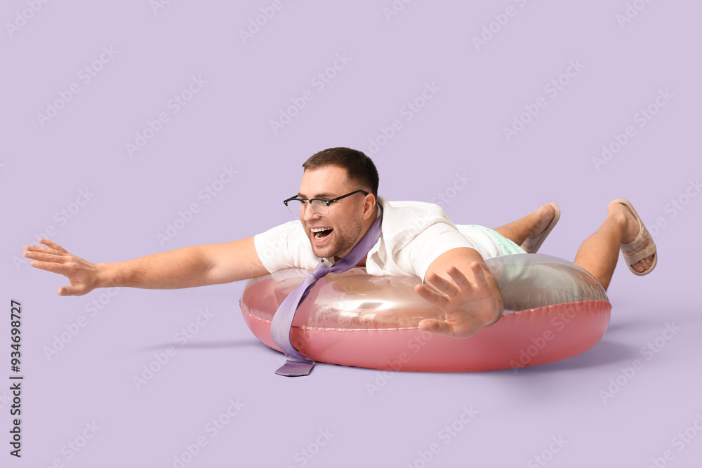 Happy office worker lying on inflatable ring against lilac background