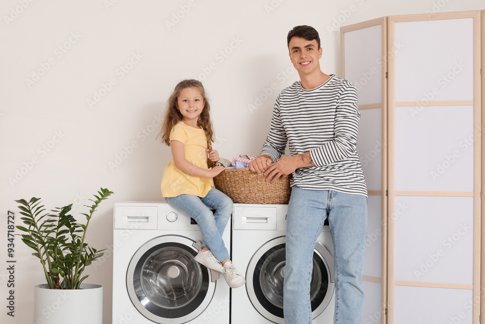 Young father and his daughter with laundry basket in bathroom