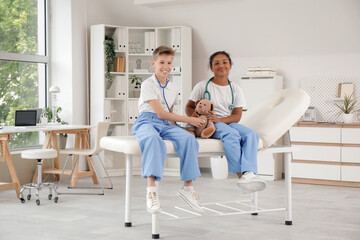 Wall Mural - Teenage doctors examining teddy bear with stethoscope in clinic