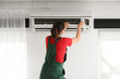 © Pixel-Shot - Female technician repairing air conditioner at home