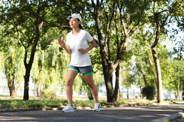 Sticker - Beautiful young happy sporty Asian woman jogging in park outdoors