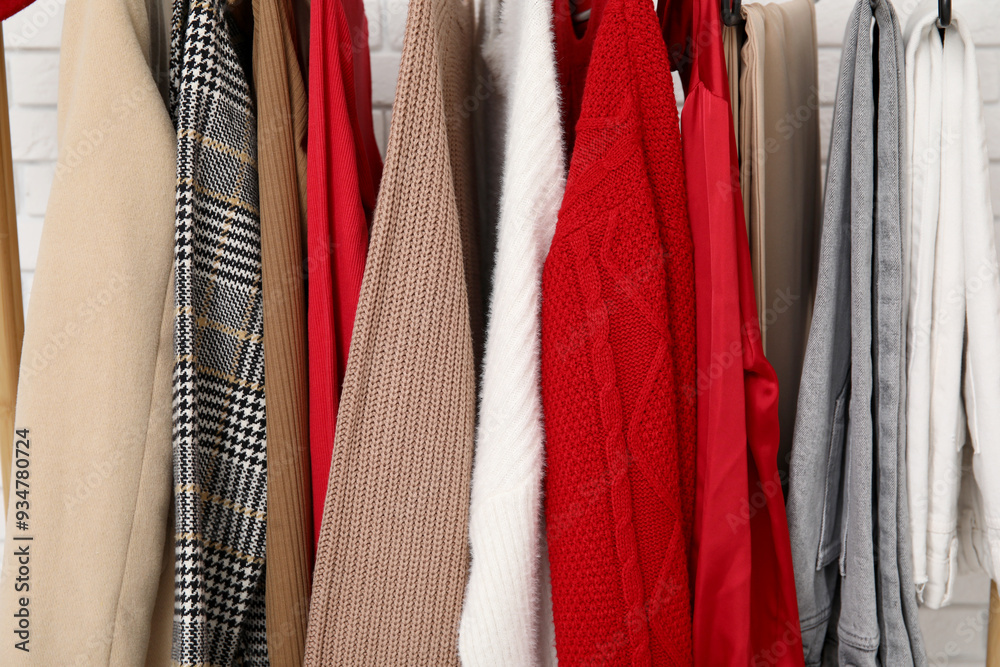 Rack with stylish clothes on white brick background. Closeup