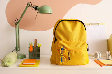 Canvas Print - Workspace with school supplies and backpack near color wall