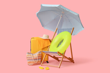 Deck chair, beach umbrella, suitcase, hat, bag, flip-flops and inflatable ring on pink background