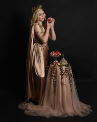 Sticker - Full length portrait of beautiful female model wearing gold grecian silk toga robes, historical fantasy goddess  persephone holding pomegranate fruit. Standing pose isolated studio background.