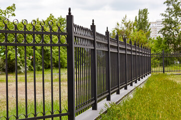 Metal fence in the city park. Decorative black iron guardrail for protection, close up