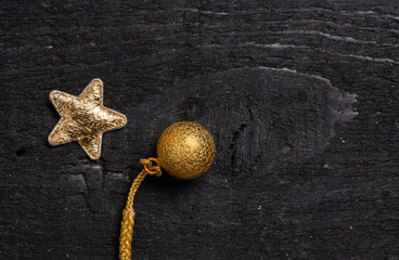 golden star and small ball decoration for New Year or Christmas on black wooden background