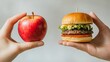 © Naphol - A hands-on comparison of a fresh apple and a delicious hamburger, showcasing choices in healthy and indulgent food options.