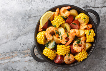 Wall Mural - Homemade Cajun Seafood Boil with shrimp, corn, baby potatoes, sausage and lemons closeup on the table. Horizontal top view from above