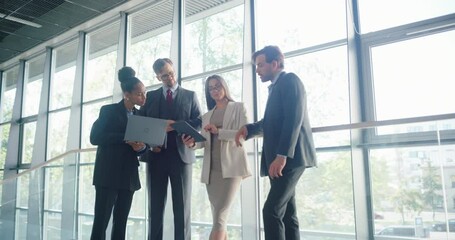 Aufkleber - Diverse Business Team Collaborating on Project Details in a Modern Office Hallway, Using Laptop Computers and Tablets. Professionals in Corporate Attire Work on report in and Bright Corridor at Work