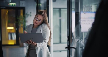 Aufkleber - Busy Female Manager Exiting an Office Room with Documents and Laptop Computer. Young Woman Talking on a Phone with a Business Client, Discussing Future Partnership and Legal Responsibilities