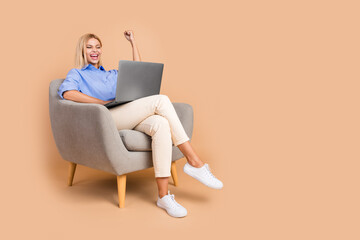 Poster - Full length photo of charming lucky woman wear blue shirt winning modern device empty space isolated beige color background