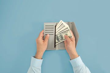 Hands holding wallet with hundreds of dollars in cash on isolated background