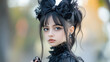 © Rutchaneewan - Gothic Elegance, a young girl with striking features adorned in black lace and bows, embodies a mysterious charm against a softly blurred outdoor background.