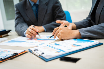 Wall Mural - close-up of two professionals' hands meeting at a desk, discussing business strategies over a digital tablet and laptop. teamwork, planning, and communication in a corporate office setting.