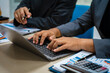 © NanSan - close-up of two professionals' hands meeting at a desk, discussing business strategies over a digital tablet and laptop. teamwork, planning, and communication in a corporate office setting.