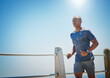 © peopleimages.com - Outdoor, black man and running in city for fitness, physical health and training for marathon by mockup. Blue sky, runner and resilience on promenade for exercise, cardio and wellness with endurance