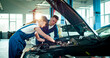 © ihorvsn - Portrait of two employees wearing specialized clothes work at service station. Young Caucasian people repair car helping each other.