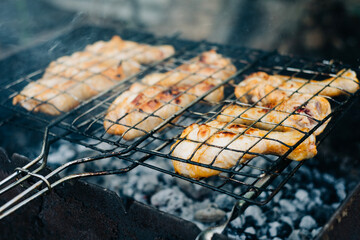 Cooking chicken legs barbecue meal on the flame with smoke on the backyard close up food photo. Meat tasty nature camping food making