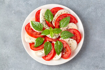 Italian caprese salad with sliced tomatoes, mozzarella, basil, olive oil