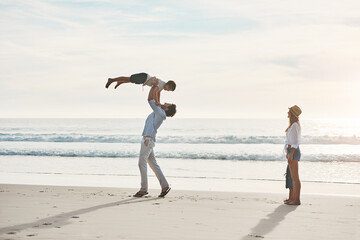 Wall Mural - Mom, dad and child on beach lift for playing on holiday, vacation and weekend together. Family, happy and young boy, mother and father by seaside for bonding, playful relationship and fun in nature