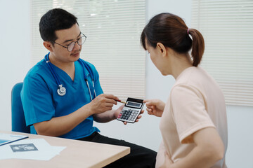 Asian female doctor listens to belly of pregnant mother during a prenatal exam in clinic. doctor provides caring advice, ensuring the health and happiness of the expecting mother and baby.