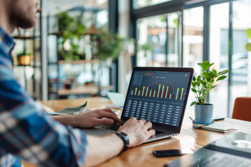 A person is focused on analyzing data on laptop, showcasing productive work environment with greenery.