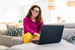 © oneinchpunch - Beautiful young woman with colorful attire working at laptop at home - Cheerful pretty female adult businesswoman remote working with computer