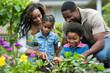 © MobiWall - A peaceful scene of a family gardening together in their backyard. They are planting flowers, watering plants, and enjoying the fresh air. The parents are teaching the children about gardening