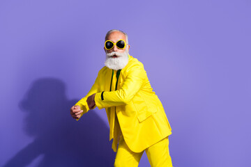 Sticker - Portrait of funny extravagant aged man dance good mood yellow suit isolated on purple color background