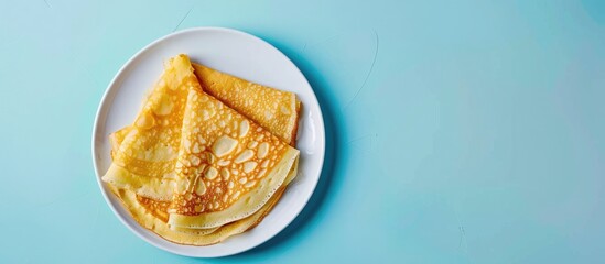 Poster - Crepes thin Russian pancakes on a white plate set against a pastel blue background Top view. Copy space image. Place for adding text and design