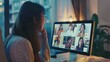 © VK Studio - A woman wearing glasses engages in a virtual meeting, attentively viewing a screen displaying several participants in individual video call windows.