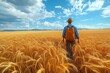 © fotofabrika - A person walking through golden wheat fields under a blue sky with scattered clouds at sunset in a rural landscape