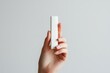 © BOONJUNG - A hand holding a white lipstick box with, Mockup cosmetics product for branding