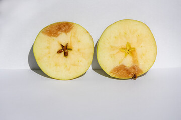 apple cut in half on a plain gray background. a little damaged, brown stain. two parts apple