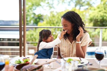 Sticker - Mom, girl and feeding by table for lunch with food for prepare feast, outdoor and together for festive holiday. Mother, daughter and home for thanksgiving celebration, tradition and bonding with love