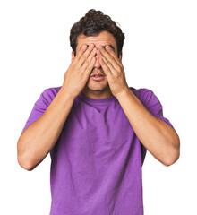 Wall Mural - Young Hispanic man in studio afraid covering eyes with hands.