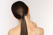 © Ольга Шефер - A young Caucasian brunette woman is experiencing neck pain, suffers from osteochondrosis, holds her hand around her neck, tilting her head sideways.