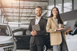 © anatoliycherkas - Super sales team in dealership, two consultants or managers in elegant suits with laptop and tablet in arms in car dealership